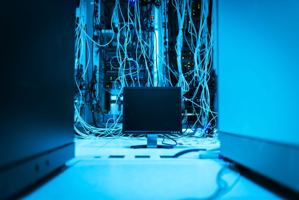 Serverschränke mit dichter Netzwerkverkabelung und einem Monitor in blauem Licht